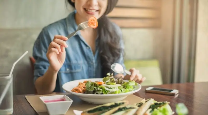 Femme mangeant un repas sain après l'entraînement pour optimiser la perte de poids et la musculation.
